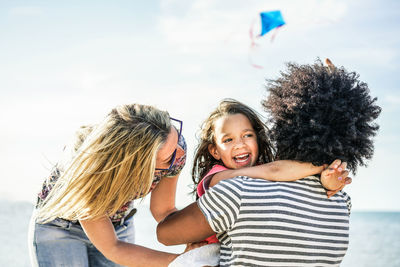 Smiling girl with parents against sky in sunny day