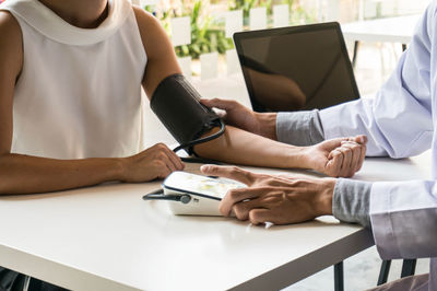 Midsection of man holding smart phone while sitting on table