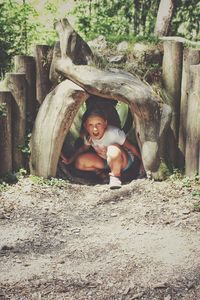 Portrait of happy boy on tree trunk