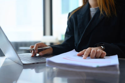 Midsection of businesswoman using laptop at office
