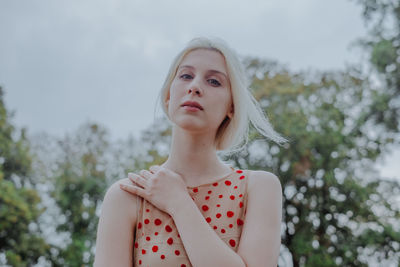 Portrait of beautiful young woman with trees in background