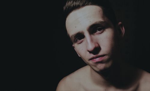 Portrait of young man against black background