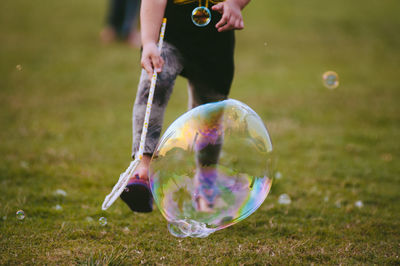 Low section of child playing with bubble on field