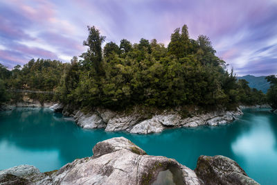 Scenic view of river by trees against sky