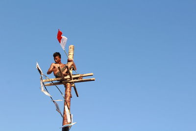 Low angle view of people against clear blue sky