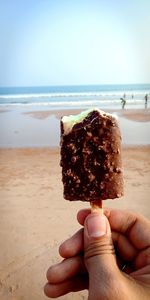 Person holding ice cream on beach