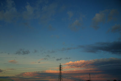 Low angle view of electricity pylon against sky during sunset