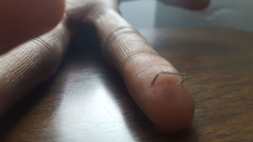 Cropped hand with staple on wooden table