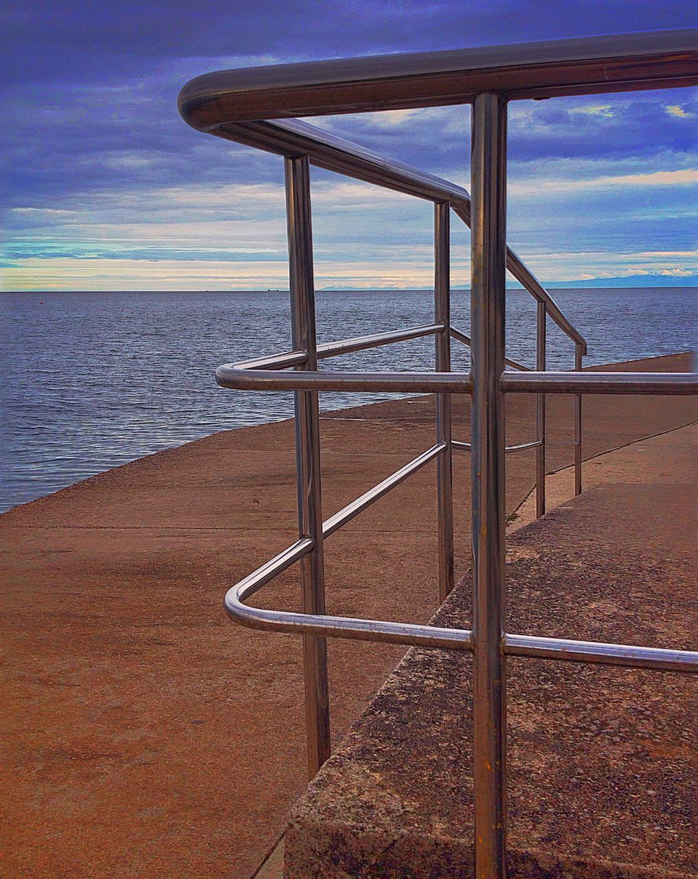 sea, water, horizon over water, sky, tranquil scene, beach, tranquility, railing, scenics, shore, built structure, nature, pier, beauty in nature, no people, idyllic, sunlight, blue, metal, calm