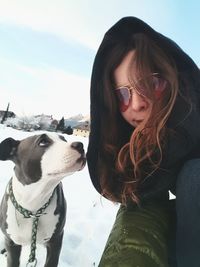 Portrait of woman with dog sitting against sky during winter
