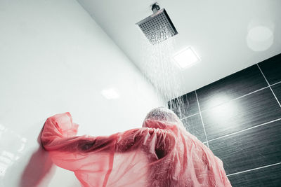 Low angle view of man in raincoat taking shower