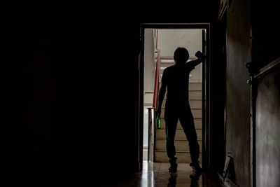 Rear view of silhouette man standing at entrance of building