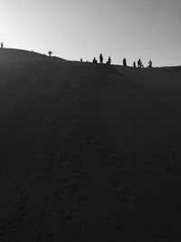 People walking in desert against clear sky