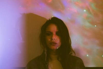 Portrait of woman standing against illuminated wall