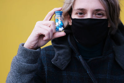 Portrait of mid adult man holding covering face against yellow background