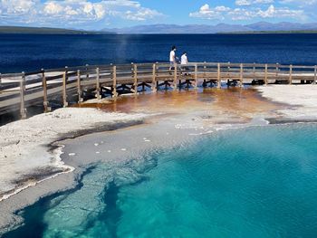 People standing by swimming pool against sea