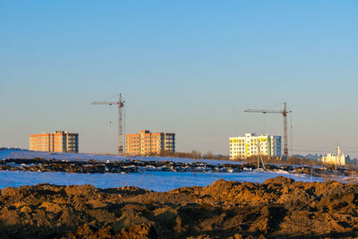 Cranes at construction site against clear blue sky