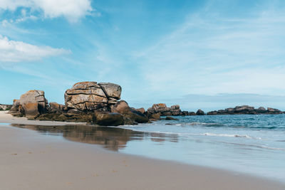 Rock formation on beach against sky