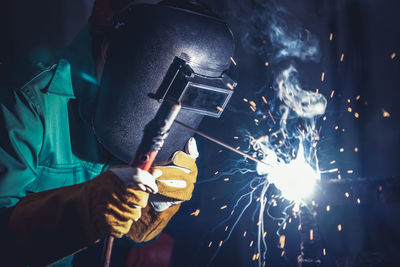 Midsection of man holding illuminated lighting equipment at night