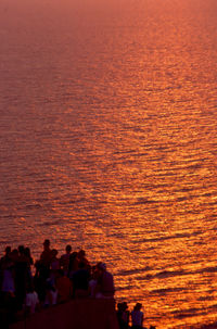Group of people on sea shore during sunset