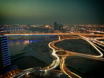 High angle view of illuminated city by road against sky at night