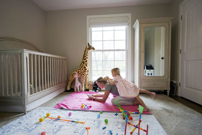 A young mom looks at her phone with her daughter on her back