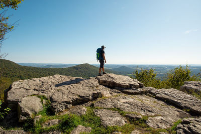 Man standing on rock against sky