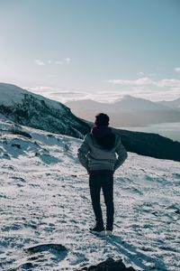 Rear view of man standing on snow covered mountain