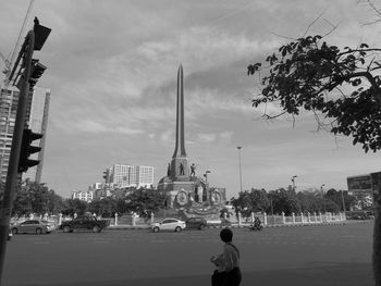 Statue in city against cloudy sky