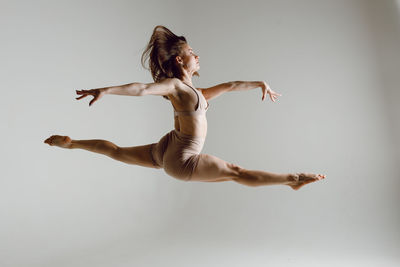 Full length of young woman jumping against white background
