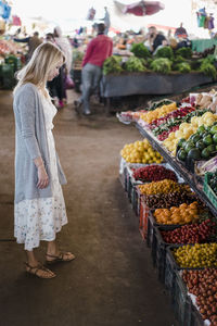 Side view of young woman looking at fruits in market