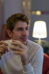 Young man holding coffee cup in cafe