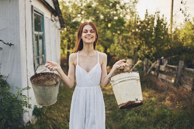 Smiling young woman standing against plants