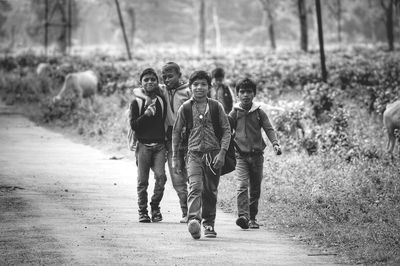 Portrait of boys with friends walking on footpath