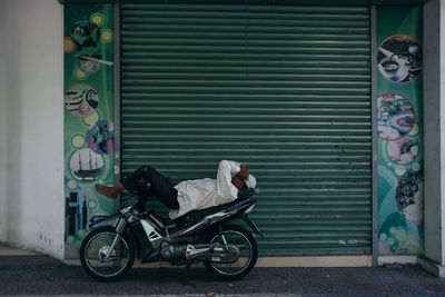 Side view of man sleeping on closed shutter