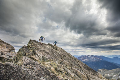 Two climbers approach the summit of a mountain peak.