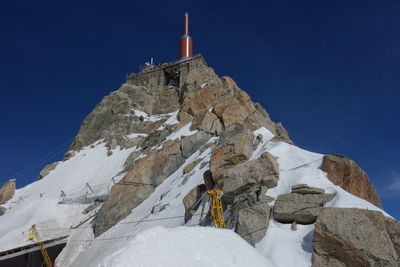 Low angle view of snowcapped mountain against clear blue sky