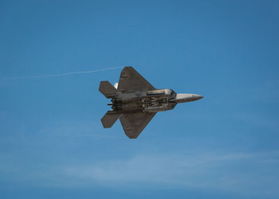 Low angle view of airplane flying against clear blue sky