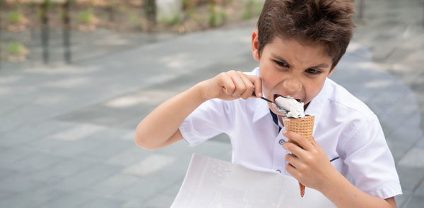 Cute child boy with a dirty face eats ice cream, the child enjoys dessert