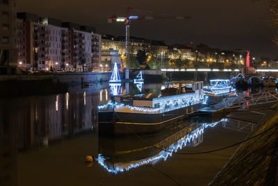 Boats moored at illuminated harbor against sky at night