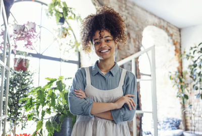 Portrait of young woman standing against window