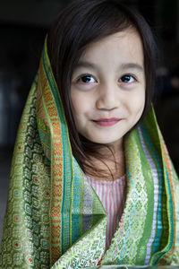 Portrait of cute asian toddler, kid, girl wearing traditional songket shawl.