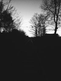 Silhouette bare trees on landscape against clear sky