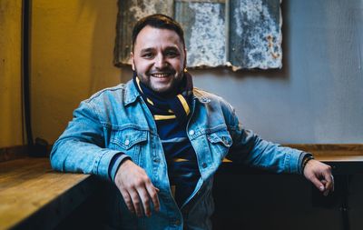 Portrait of smiling young man standing against wall