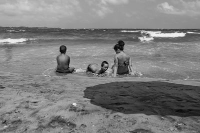 Rear view of men sitting on beach