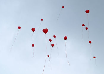 Low angle view of red balloons flying against clear sky