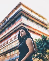 Low angle view of young woman standing outside building