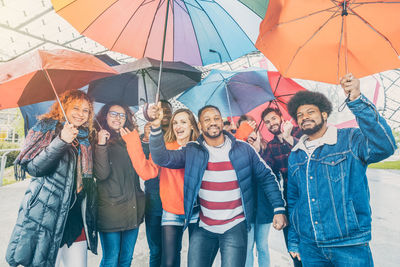 Portrait of multi-ethnic friends holding umbrella