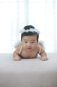 Portrait of cute baby girl lying on bed