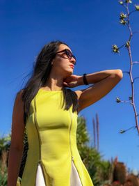 Low angle view of young woman standing against sky